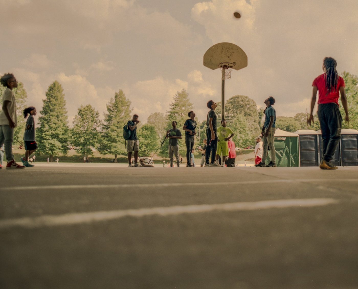 Young men playing basketball on an outdoor court in Atlanta.