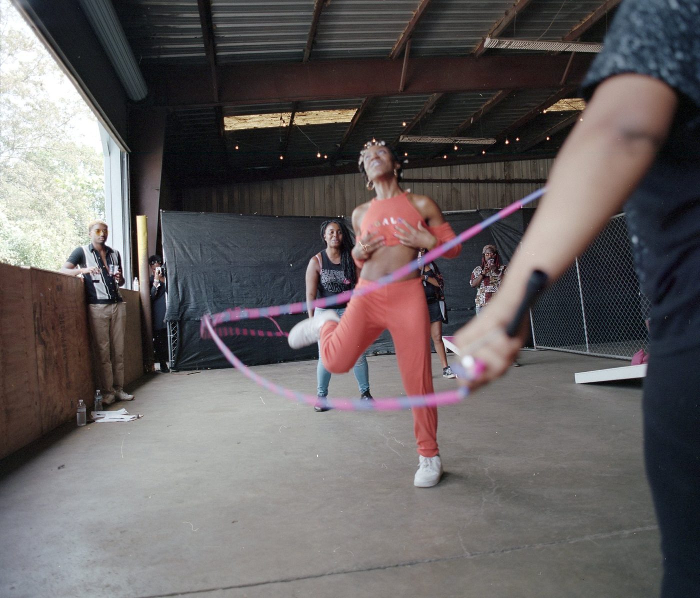 A woman mid-jump in double dutch inside an open warehouse, ropes arcing through the frame.